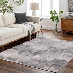 a living room with a couch, chair and rug on the hardwood floor in front of a window