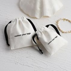 two bags sitting on top of a white table next to a pearl beaded necklace