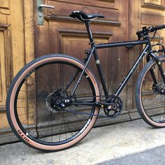 a black bike parked in front of a wooden door with brown trim and spokes