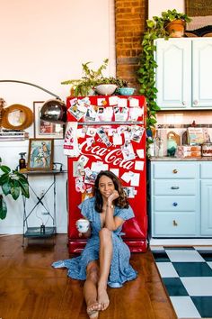 a woman sitting on the floor in front of a coca - cola machine