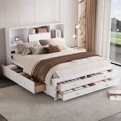 a white bed with drawers underneath it in a bedroom next to a large glass window