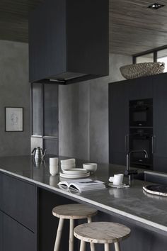 two stools are in front of the kitchen counter and island with plates on it