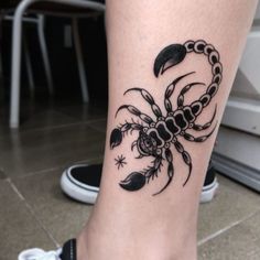 a woman's foot with a scorpion tattoo on her left leg and an arrow in the middle