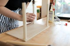 a woman is making something out of wood and glue on the counter top with her hands