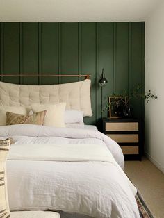 a bedroom with green walls and white bedding