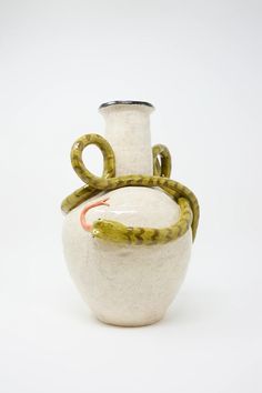 a white and green vase with two snakes on it's side, sitting in front of a white background