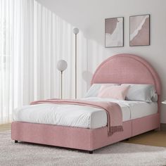 a pink bed sitting in a bedroom next to a white rug and window with curtains