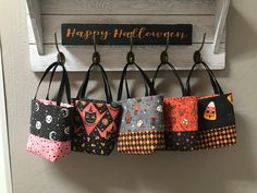 a group of purses hanging from hooks on a door hanger that says happy halloween