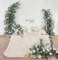 a table with flowers and candles on it in front of a wall that says richart