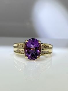 a yellow gold ring with an amethyst purple stone and diamond accents on the band