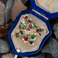 This wonderful ring features two (2) round brilliant cut diamonds, three (3) round mixed cut emeralds, rubies and sapphires, bead set in individual dishes. The ring measures 23.2mm at the top, rises 8.6mm above the finger, tapering to 1.7mm wide and 1.4mm thick at the base of the shank. This ring is currently a size 7.25. Emerald Multi-stone Round Cut Ring, Multi-stone Round Cut Emerald Ring, Round Cut Multi-stone Emerald Ring, Round Multi-stone Emerald Ring, Yellow Gold Multi-stone Emerald Birthstone Ring, Emerald Multi-stone Birthstone Ring Gift, Round Multi-stone Diamond Emerald Ring, Multi-stone Emerald Diamond Ring As Gift, Heirloom Multi-stone Round Emerald Ring