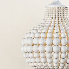 a large white light hanging from a ceiling fixture with lots of balls attached to it