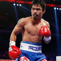 a man standing on top of a boxing ring wearing red and white gloves with one hand in the air