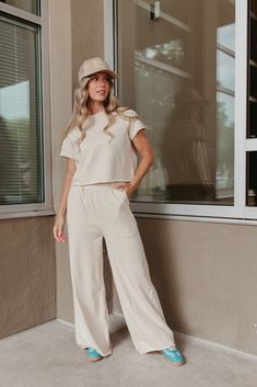 Look super cute and feel comfortable all day in THE SARA SET IN CREAM! This travel outfit includes a raw hem, cropped short sleeve sweater and wide leg pants with an elastic waist. Perfect for wearing all day, this set is both stylish and comfortable. Paired with THE HOWDY DARLIN' TRUCKER HAT IN BEIGE & THE FIERCE SNEAKERS IN GREEN Sold as a set. Top: Short sleeve Round neck Raw hem Slightly cropped Loose fit 80% polyester, 20% spandex Bottom: Wide leg Pockets Relaxed fit Elastic waistband Raw h Casual Sets With Elastic Waistband And Wide-leg Pants, Casual Set With Elastic Waistband And Wide-leg Pants, Casual Beige Wide Leg Sets, Cropped Wide Leg Summer Loungewear Pants, Summer Cropped Wide Leg Loungewear Pants, Summer Cropped Wide Leg Pants For Loungewear, Summer Cropped Wide Leg Lounge Pants, Casual Cropped Sets For Day Out, Casual Wide Leg Sets For Day Out