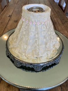 a white lamp shade sitting on top of a wooden table next to a metal plate