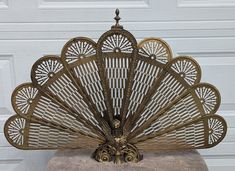 a decorative metal fan sitting on top of a stool