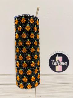 an orange and black beaded tumbler next to a sticker that says tatlicana