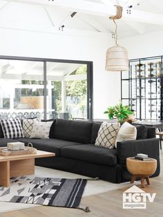 a living room with black couches and white rugs on the hardwood flooring