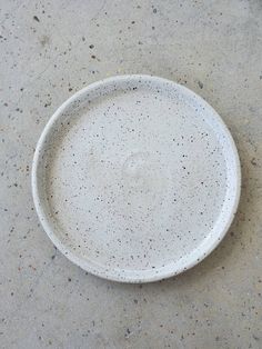 a white plate sitting on top of a cement floor