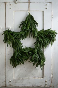 a wreath made out of evergreen branches hanging on a door