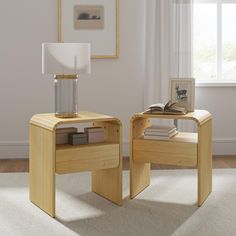 two wooden tables with books on them in front of a white curtained window, one has a lamp and the other is a book