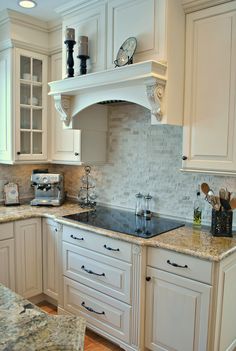 a kitchen with white cabinets and marble counter tops