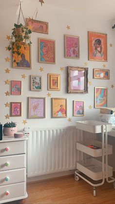 there are many framed pictures on the wall in this child's room, including princesses