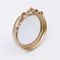 a gold colored ring with flowers on the side and a mirror in the middle, against a white background