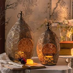 two decorative vases sitting on top of a table next to each other with candles in them