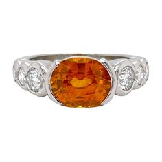 Timeless orange sapphire and diamond ring in 18k white gold. Ring contains 1 center 9x7mm oval orange sapphire set in a half bezel weighing 3.12ct and 6 graduating round brilliant diamonds set in a full bezel weighing 0.91tcw. Diamonds are G in color and SI1 in clarity, excellent cut. Ring is finger size 5.75 and and be resized to desired measurement. All of our pieces are packaged carefully and accompanied by a Pico box to keep your jewelry item safe. A complimentary appraisal can be sent after Half Bezel, Bezel Engagement Ring, Sapphire And Diamond Ring, Orange Sapphire, Sapphire Diamond Ring, White Gold Ring, Sapphire Diamond, Cocktail Rings, Round Brilliant