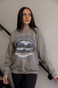 Experience the beauty of nature with our Washington Mount Rainier sweatshirt. Inspired by vintage designs, this graphic sweatshirt showcases the majestic Mount Rainier in soft shades of grey. Perfect for outdoor enthusiasts and fashion lovers alike. distressed vintage inspired graphic long sleeves crew neck relaxed fit model is wearing a s/m Gray Sweatshirt For Outdoor Fall Activities, Oversized Graphic Print Sweatshirt For Outdoor, Spring Outdoor Sweatshirt With Letter Print, Oversized Gray Sweatshirt For Outdoor, Outdoor Letter Print Sweatshirt For Spring, Spring Outdoor Sweatshirt With Relaxed Fit, Fall Hiking Sweatshirt With Letter Print, Fall Hiking Crew Neck Sweatshirt, Fall Hiking Sweatshirt Crew Neck