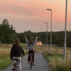 two people riding bikes on a path at dusk with the sun setting in the background