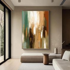 an abstract painting hangs on the wall above a couch in a living room with large windows