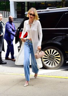 a woman in white shirt and jeans walking down the street