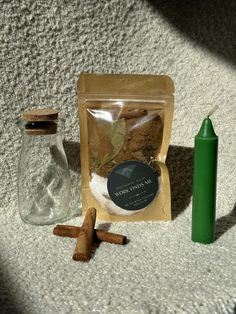 a bag of cinnamons next to two bottles and a green candle on the floor