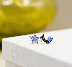 Discover the perfect blend of celestial charm and timeless elegance with our stunning tiny 925 sterling silver blue lab created opal moon and star stud earrings. Handcrafted with meticulous attention to detail, these enchanting earrings are rhodium plated for a luxurious finish and enhanced durability. Measuring at a delicate 7mm, they are the ideal accessory to add a touch of sparkle to your everyday look or to complement a special occasion outfit. The post back ensures a secure and comfortable fit, making them perfect for all-day wear. Crafted from high-quality 925 sterling silver, these earrings feature dazzling blue lab created opal inlays that capture the mesmerizing beauty of the night sky. The moon and star design brings a whimsical yet sophisticated touch to your jewelry collection Sterling Silver Celestial Earrings For Gift, Celestial Sapphire Sterling Silver Jewelry, Celestial Style Sapphire Jewelry In Sterling Silver, Celestial White Gold Sterling Silver Earrings, Occasion Outfit, Star Stud Earrings, Mesmerizing Beauty, Star Earrings Stud, Celestial Jewelry