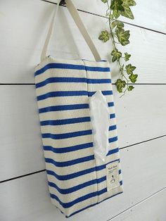 a blue and white striped tote hanging on a wall next to a potted plant