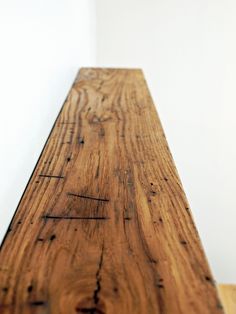 a wooden bench sitting on top of a hard wood floor next to a white wall