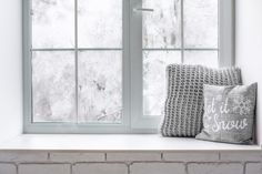 two pillows sitting on top of a window sill in front of a brick wall