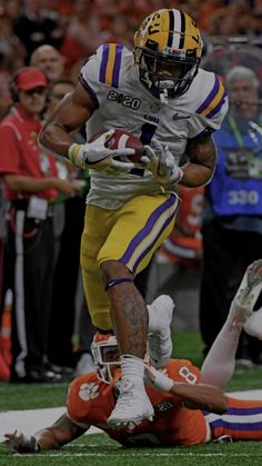 a football player running with the ball in his hand and people watching from the sidelines