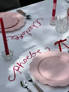 the table is set with pink plates, silverware and red candles for an elegant valentine's day celebration