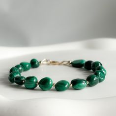 "Our Maia bracelet is the cutest statement piece with genuine Malachite gems. With forest green tones, it is the perfect colour to match any outfit.  PROPERTIES * Support positive transformation * Encourages an abundant mindset  * Opens the heart to love   MATERIALS & COMPONENTS * Made with Genuine Malachite beads & your choice of Sterling Silver or 14k Gold Filled Findings  * Tarnish resistant * Skin friendly * 6\" with a 2\" extender * 7-10mm Malachite beads  * Arrives in a rose petal filled gift box, your jewellery in a cotton baggie & a pink jewellery cleaning cloth.    JEWELLERY CARE  * Avoid swimming in the sea & swimming pools  * Avoid wearing your jewellery when showering and exercising * Put on perfumes and lotions before putting on your jewellery  * If your pieces get wet, pat it Luxury Malachite Jewelry With Polished Beads, Swimming In The Sea, Sea Swimming, Malachite Bracelet, Malachite Jewelry, Chunky Bracelet, Chunky Bracelets, Pink Jewelry, Old Jewelry