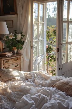 an unmade bed with white sheets and pillows in front of two windows that look out onto the outdoors