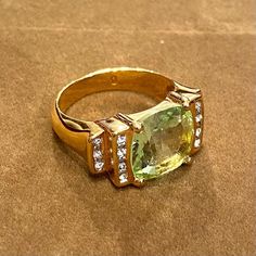 a yellow gold ring with an oval cut stone surrounded by small round diamonds on a brown surface