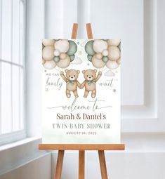 two teddy bears holding balloons on top of an easel for a baby shower sign