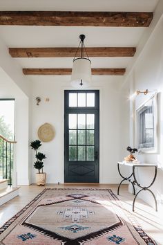 a large rug in the middle of a room with a black door and wooden beams