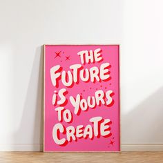 a pink poster that says the future is yours to create on it in front of a white wall