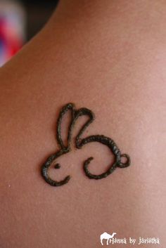 a tattoo on the back of a woman's shoulder with a rabbit drawn on it