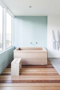 a bathroom with a large tub and wooden flooring next to a wall mounted window