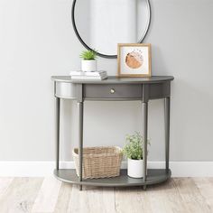 a small table with a basket on it next to a mirror and potted plant